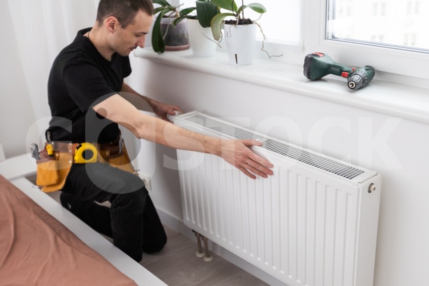 plumber at work. Installing water heating radiator